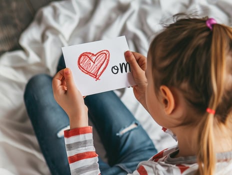 Little girl giving her hand writing greeting card to her mom. photo