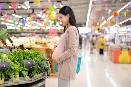 Beautiful pregnant woman shopping healthy food at grocery shop photo