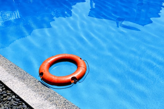Orange lifebuoy floating on surface swimming pool photo