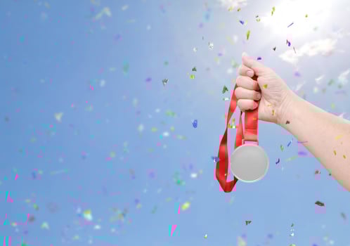 Holding a silver medal coin celebrating success sky background photo