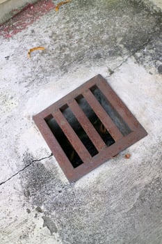 an iron gutter cover, with a rust color. Box shaped. on a concrete road photo