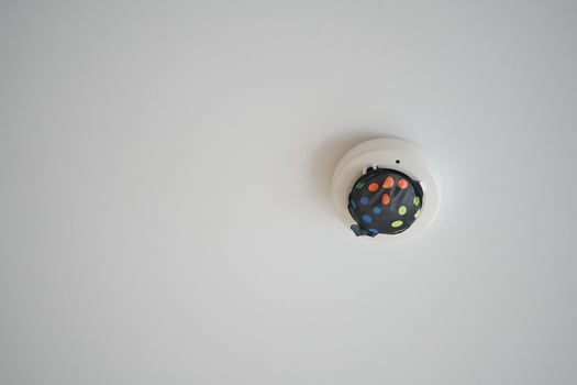 White smoke detector on ceiling at home photo