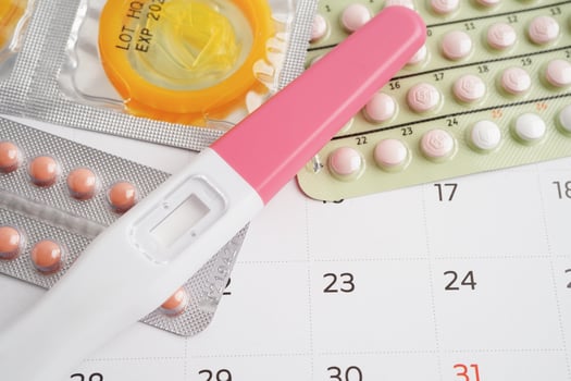Pregnancy test with birth control pills and condom for female on calendar, ovulation day. photo