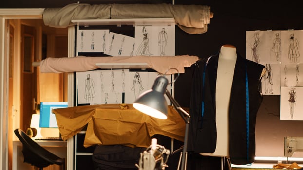 Industrial mannequin and drawings in sewing shop, tools used to create custom made clothing line. Human figure doll dressed in fabric, manufacturing process with meter and pins in atelier. photo
