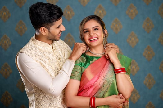 Picture Of An Indian Married Couple Wearing Traditional Outfits Giving A Surprise Gift During A Festival photo