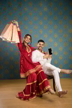 A Young Couple Enjoying Themselves While Holding Shopping Bags And Sitting On A Chair In Front Of The Camera photo