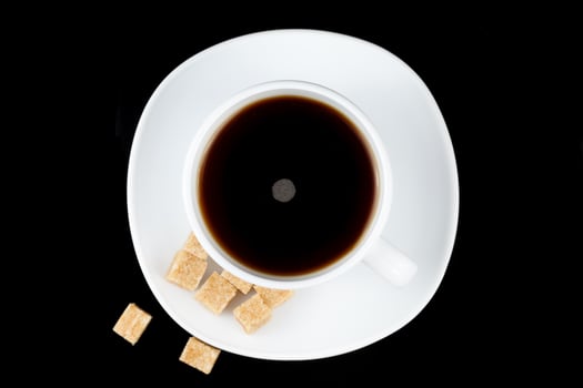 Coffee in a cup with a piece of brown sugar. Coffee on a black background photo