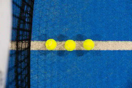 balls near the net of a blue padel tennis court photo