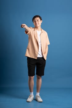 Portrait of Asian man posing on blue background, traveling in summer photo