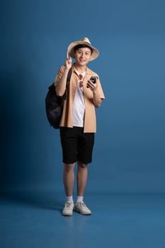 Portrait of Asian man posing on blue background, traveling in summer photo