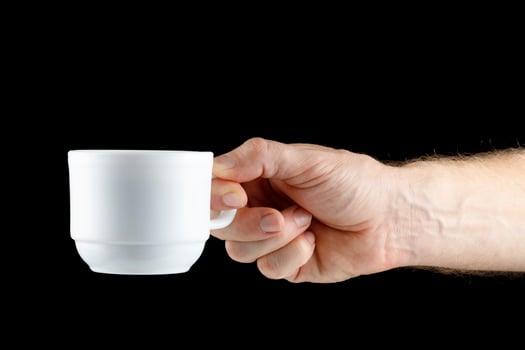 Hand holding white cup on black isolate photo