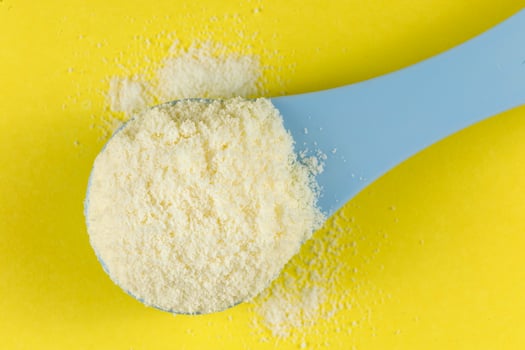 Baby food and a blue spoon. Yellow powder for baby food. photo