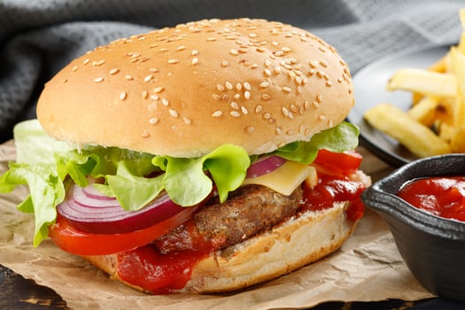 Burger with cutlet, tomato, cheese and greens. Fresh tasty burger isolated on black background photo