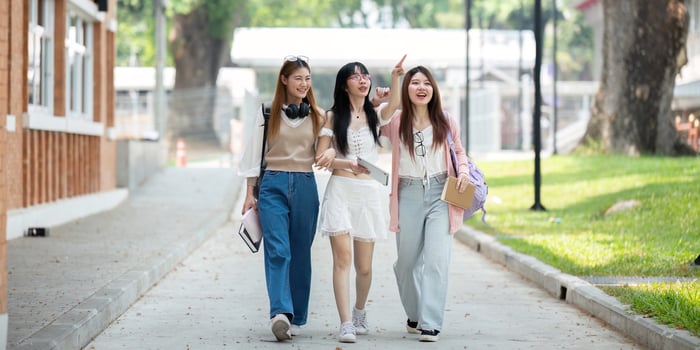 College friends walk to class together. University student in campus talk and have fun outdoors photo