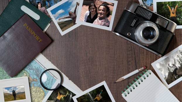 Couple photographs, passports, old camera, map and notebook on a dark wooden table photo
