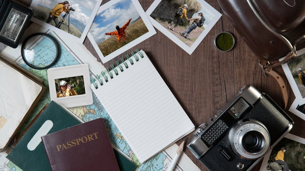 Couple photographs, travel photos, passports, old camera, map and notebook on a dark wooden table photo