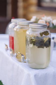 water from jug pouring into glass on wooden table outdoors photo