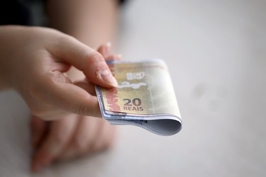Brazilian money bills in woman hand. Female gives bunch of brazilian reais to us photo