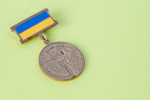 Military medal with the Ukrainian flag. The inscription in Ukrainian is War Veteran . Motherland holds a shield and sword. Ukraine, Kyiv - February 24, 2022. photo