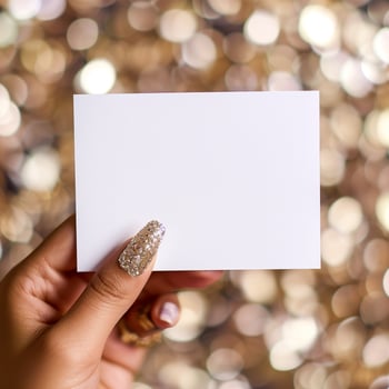 Blank white note card in hand with gold glitter background. photo
