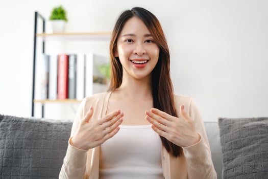 A young deaf woman is sitting on a couch and making a sign Language to communicate. photo