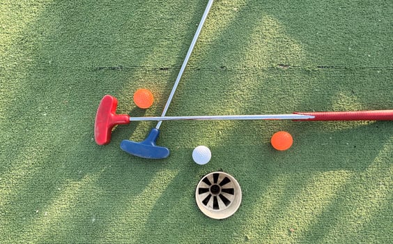 Golf ball and golf club on green in the evening golf course with sunshine photo