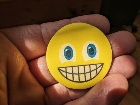 Closeup of hand holding yellow smiley face, emotions concept, happiness background, template photo