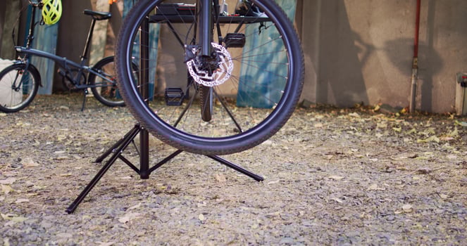 Detailed view of damaged bike mounted on repair-stand ready for repair with assortment of tools outdoor. Annual summer upkeeping and servicing of modern bicycle in home yard. photo