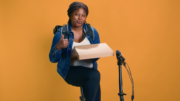 Friendly courier on bicycle carrying package from restaurant for timely reliable courier service. Black woman holding pizza box and giving thumbs up ensuring fresh sustainable food delivery. photo