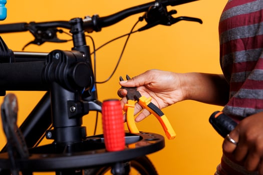 Detailed shot of a black woman hand holding and arranging bicycle servicing equipment. Close-up of a plier and other specialized tools being organized on bike repair stand by african american person. photo