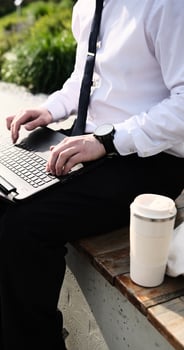 Caucasian bearded business man freelancer working on break with laptop outdoors in park. Male office worker sitting on a bench on a city street park on a modern urban background Workplace outside photo