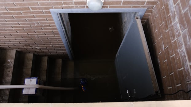 Recently flooded basement seen with a large pipe and pump used to pump out flooded basement water. The flooded basement of the house photo