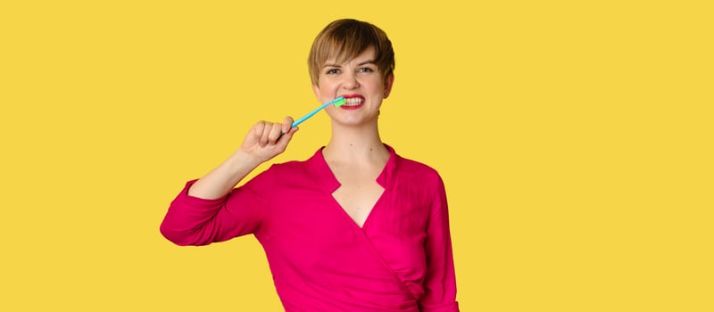 A smiling woman with healthy teeth holds a toothbrush in her hands. A young beautiful girl on a bright background. Oral hygiene. A place for your text. photo