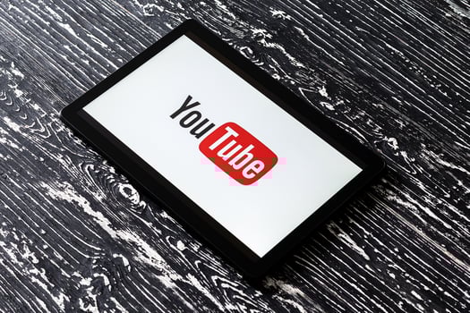 Tablet computer on a black wooden table with a social network YouTube logo on the screen. photo