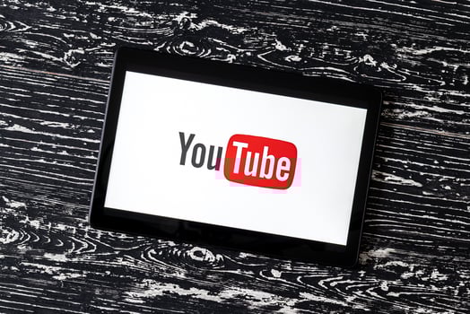 Tablet computer on a black wooden table with a social network YouTube logo on the screen. photo