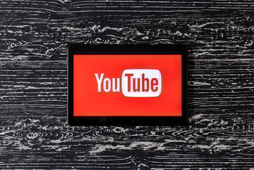 Tablet computer on a black wooden table with a social network YouTube logo on the screen. photo