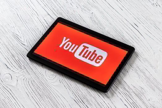 Black tablet computer on a white wooden table with a social network YouTube logo on the screen. photo