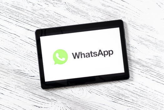 Black tablet computer on a white wooden table with a messenger WhatsApp logo on the screen. photo