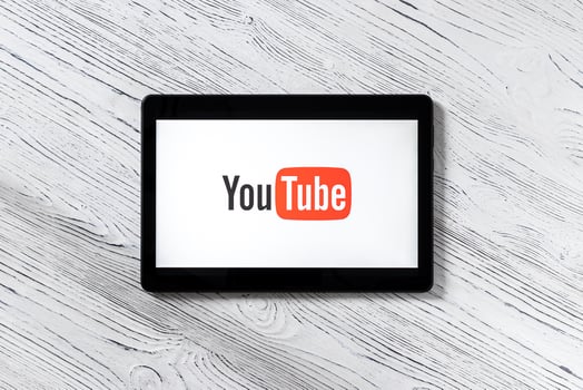 Black tablet computer on a white wooden table with a social network YouTube logo on the screen. photo