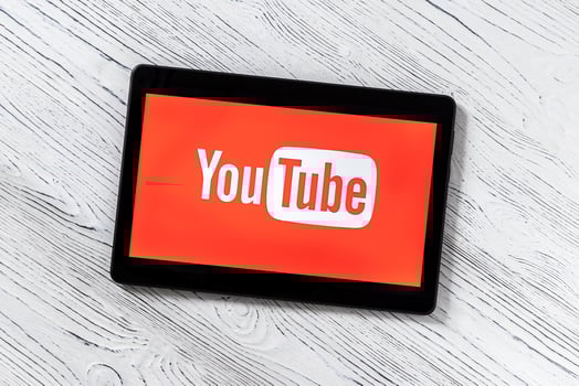 Black tablet computer on a white wooden table with a social network YouTube logo on the screen. photo