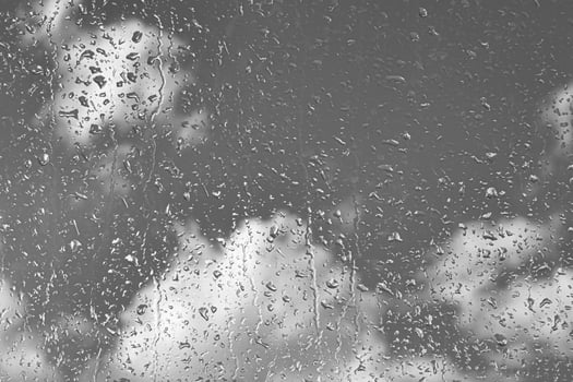 Rain drops on window glasses surface with gray sky background. Natural backdrop of raindrops. The concept of bad rainy weather. photo