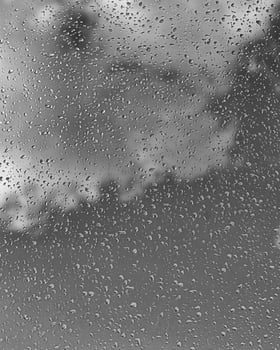Rain drops on window glasses surface with gray sky background. Natural backdrop of raindrops. The concept of bad rainy weather. photo