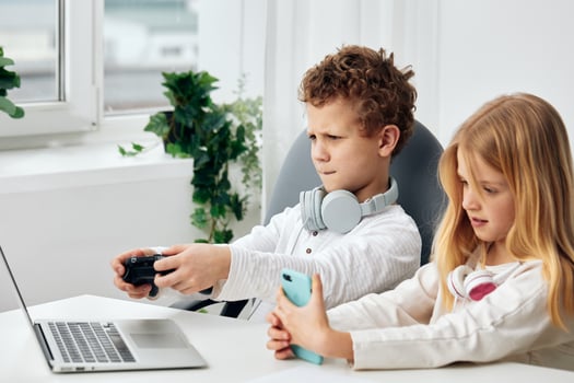 Young boy and girl happily studying together on their laptops, immersed in online learning They sit photo