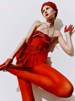 Elegant woman in a red dress lying on the floor with hands on knees in a graceful pose photo