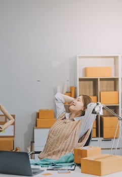 Owners of small online shopping taking a break with her hands behind her head and sitting on a chair in her workshop, relax concept photo