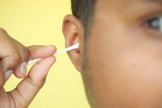 Closeup of young man using ear cotton bar photo