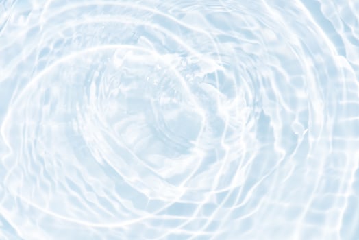 Bluewater waves on the surface ripples blurred. Defocus blurred transparent blue colored clear calm water surface texture with splash and bubbles. Water waves with shining pattern texture background. photo