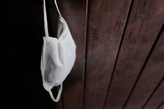 A white cloth mask for prevent the Covid-19 or Corona virus and protect for Air Pollution Value Pm 2.5 hanging on wooden doors. Health and Disease Concept photo