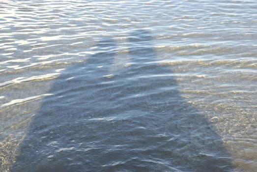 Shadow of a couple on a beach with water ripples in a sunny summer day photo