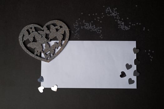 Valentine's day,a Declaration of love. Silver heart with butterflies. Butterflies in the stomach. Silver heart with butterflies on a dark graphite background.And a white envelope for the inscription photo